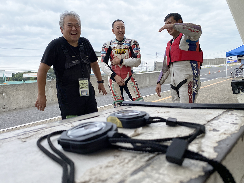 ピットの壁の上に置かれたストップウォッチごしに談笑している私と、Hさんと、酒井さんの3人。